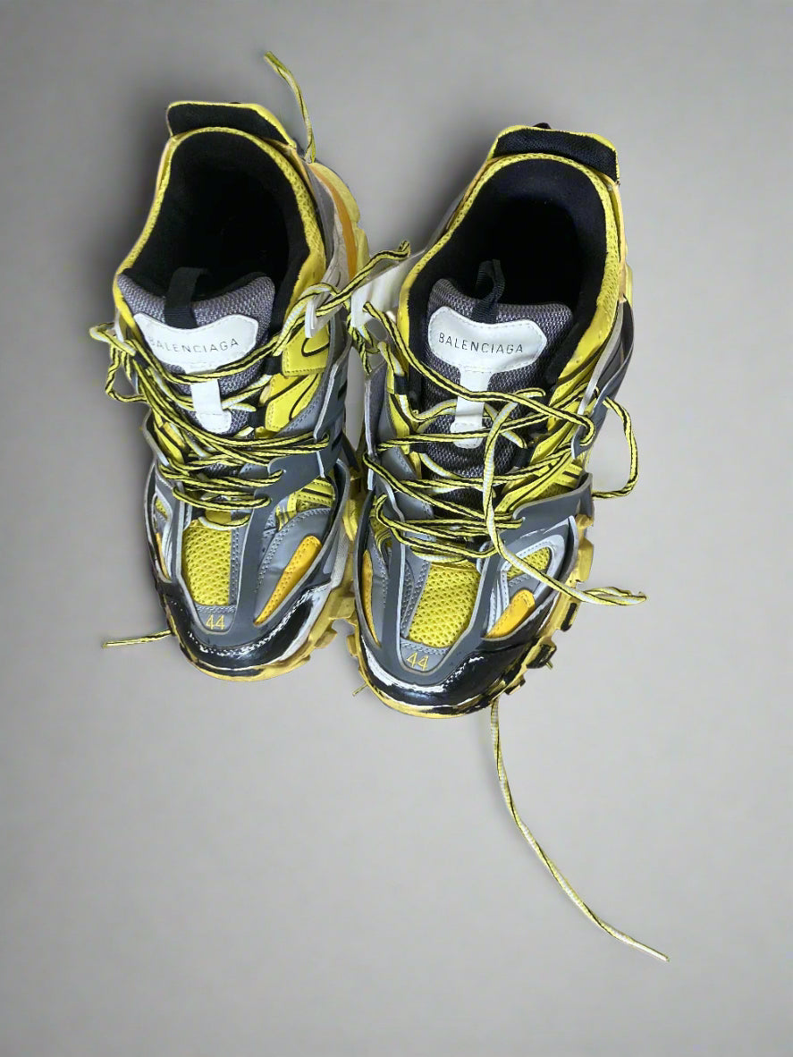 Pair of black and yellow sneakers on a brown surface