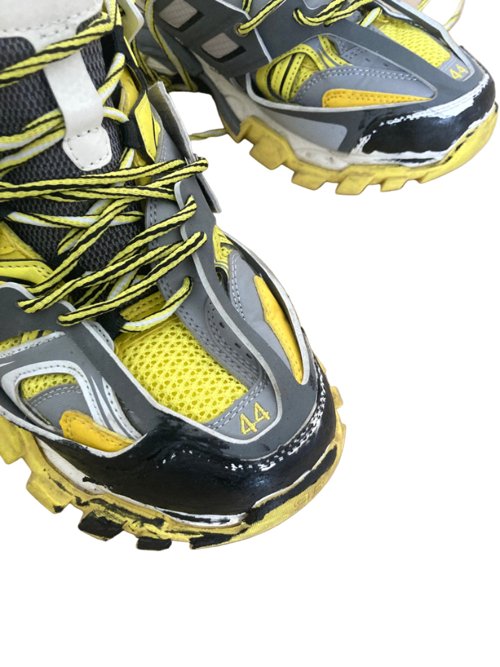 Close-up of black, yellow, and gray athletic shoes on a beige surface