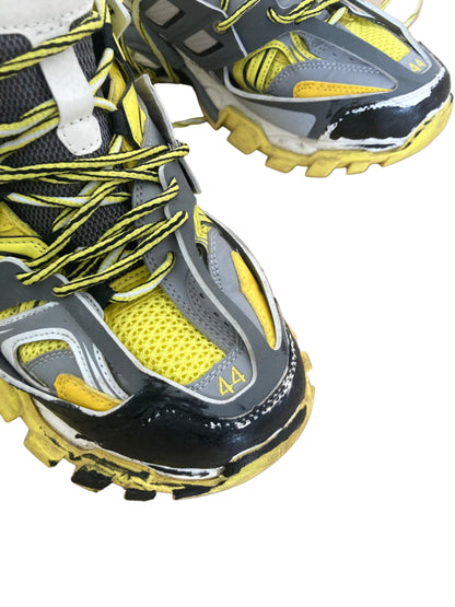 Close-up of black, yellow, and gray athletic shoes on a beige surface